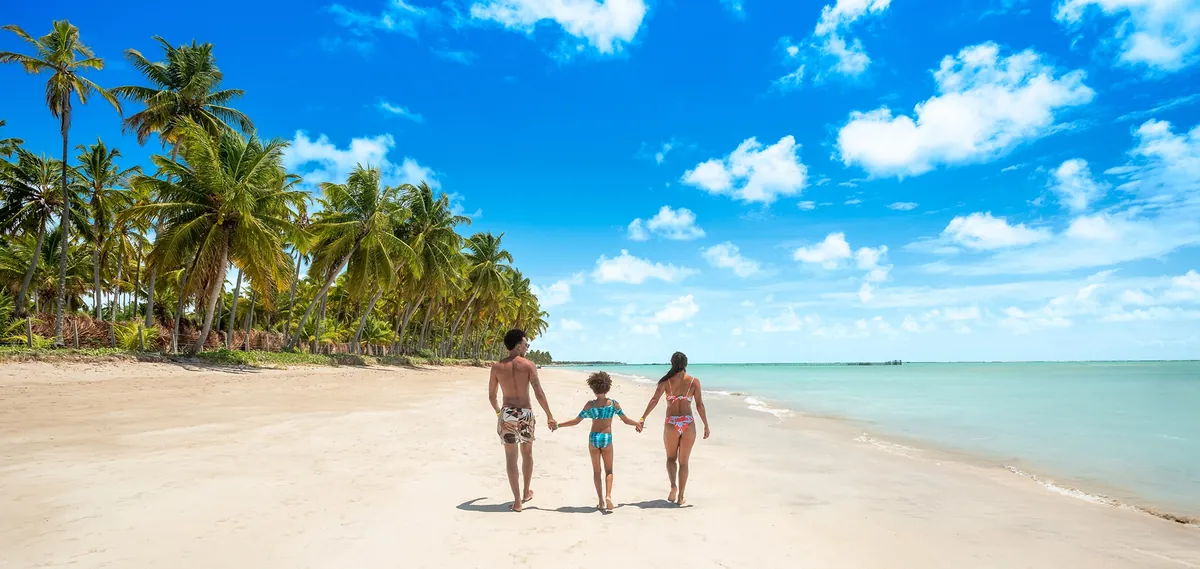 Fam&iacute;lia caminhando na praia de Maragogi em frente ao Salinas